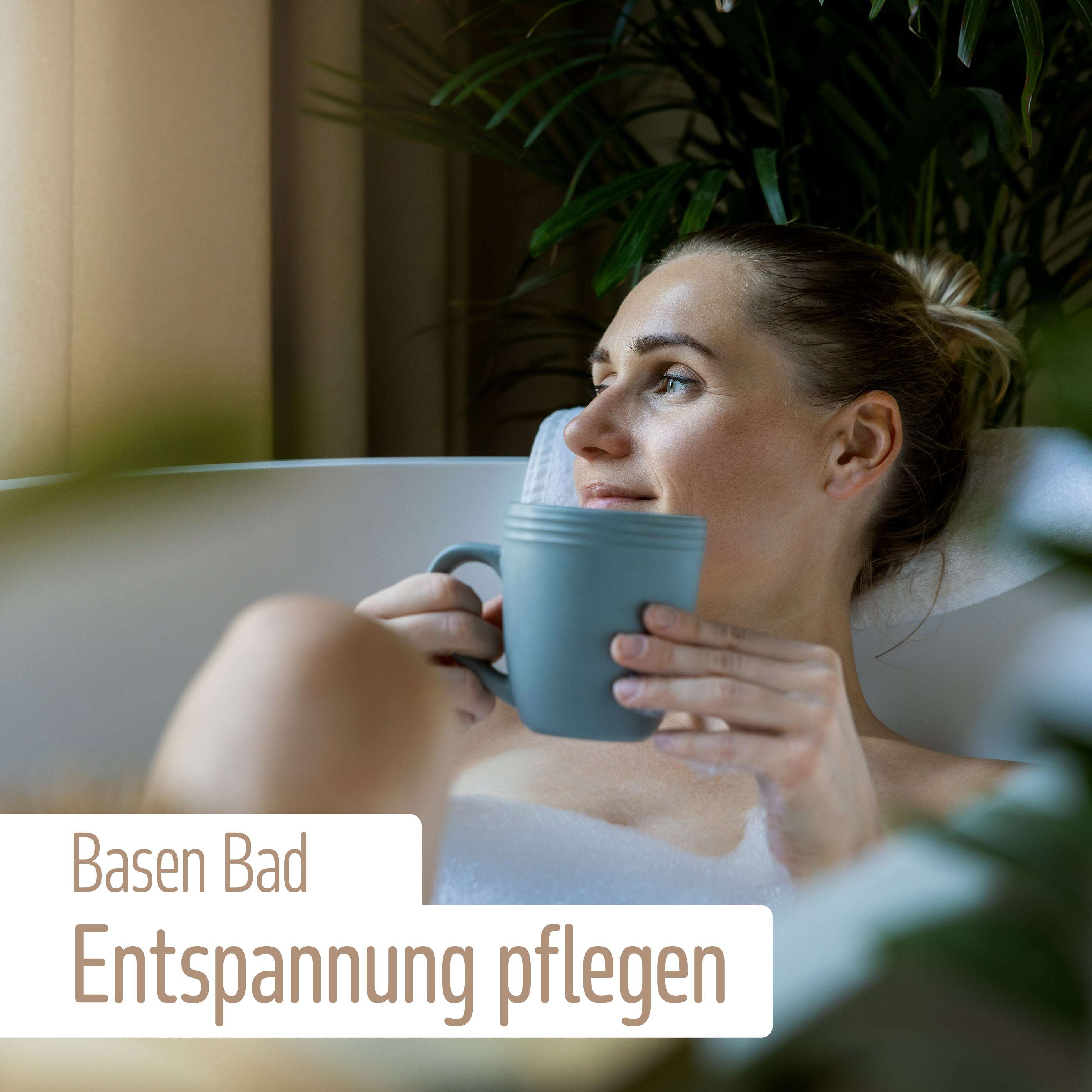 Eine Frau entspannt sich in einem Schaumbad mit einem blauen Becher, umgeben von grünen Pflanzen. Der deutsche Text lautet: Basen-Bad Entspannung pflegen – mit basisch-mineralischem Badesalz von fitne für die Säure-Basen-Balance.