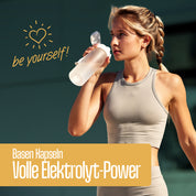 Eine fitte Frau in beiger Sportkleidung trinkt im Freien Wasser. Im Text steht "be yourself!" mit einem Herz, und auf einem gelben Banner steht: FITNE Health Care Basen Kapseln (Relaunch) - Volle Elektrolyt-Power für deine Säure-Basen-Balance.