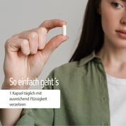 Eine Frau in einem grünen Hemd hält eine weiße Kapsel mit Magnesium + Vitamin E Kapseln in der Hand. Deutscher Text: So einfach geht’s. 1 Kapsel täglich mit ausreichend Flüssigkeit verzehren – für deinen Energiefluss mit Magnesium.
