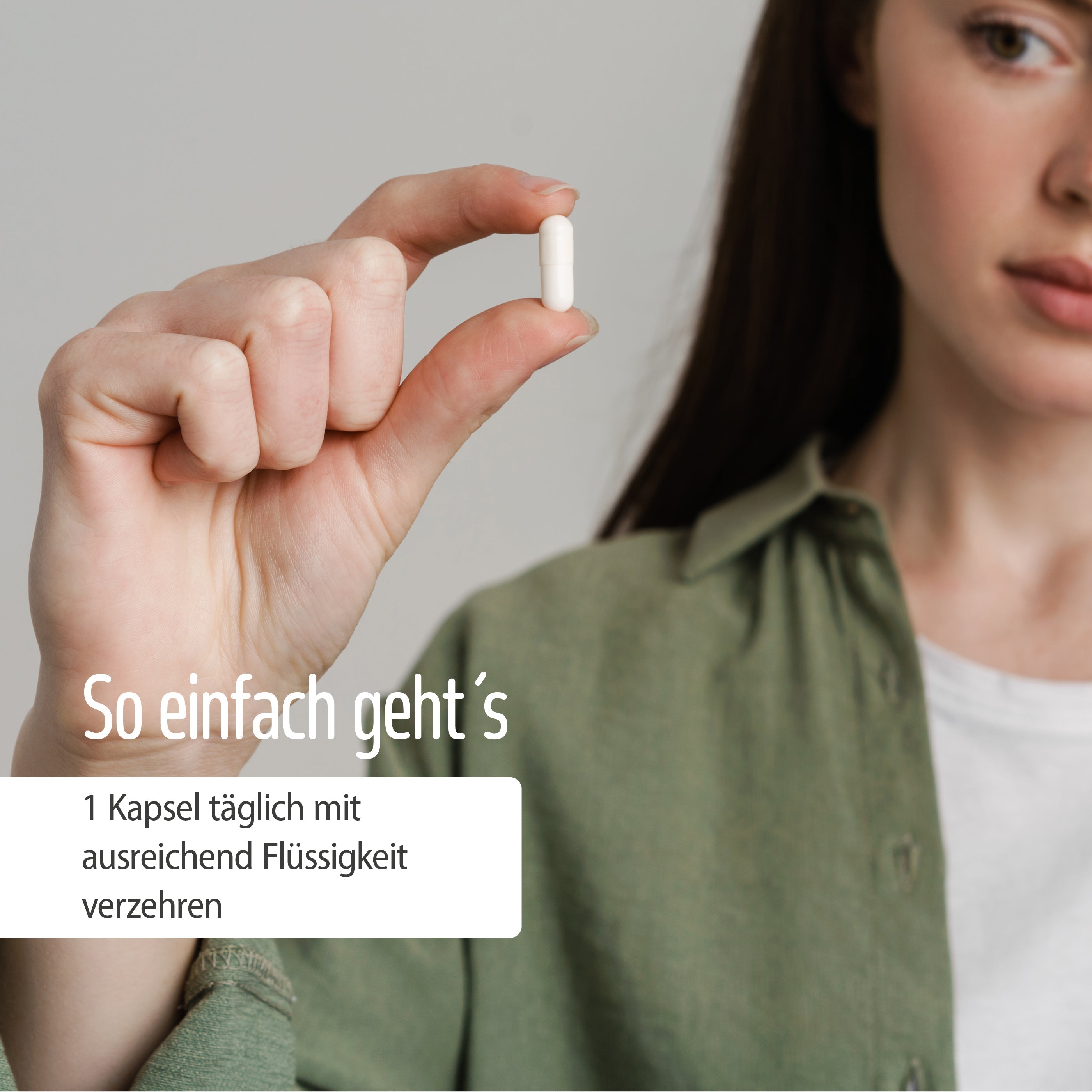 Eine Frau in einem grünen Hemd hält eine weiße Kapsel mit Magnesium + Vitamin E Kapseln in der Hand. Deutscher Text: So einfach geht’s. 1 Kapsel täglich mit ausreichend Flüssigkeit verzehren – für deinen Energiefluss mit Magnesium.