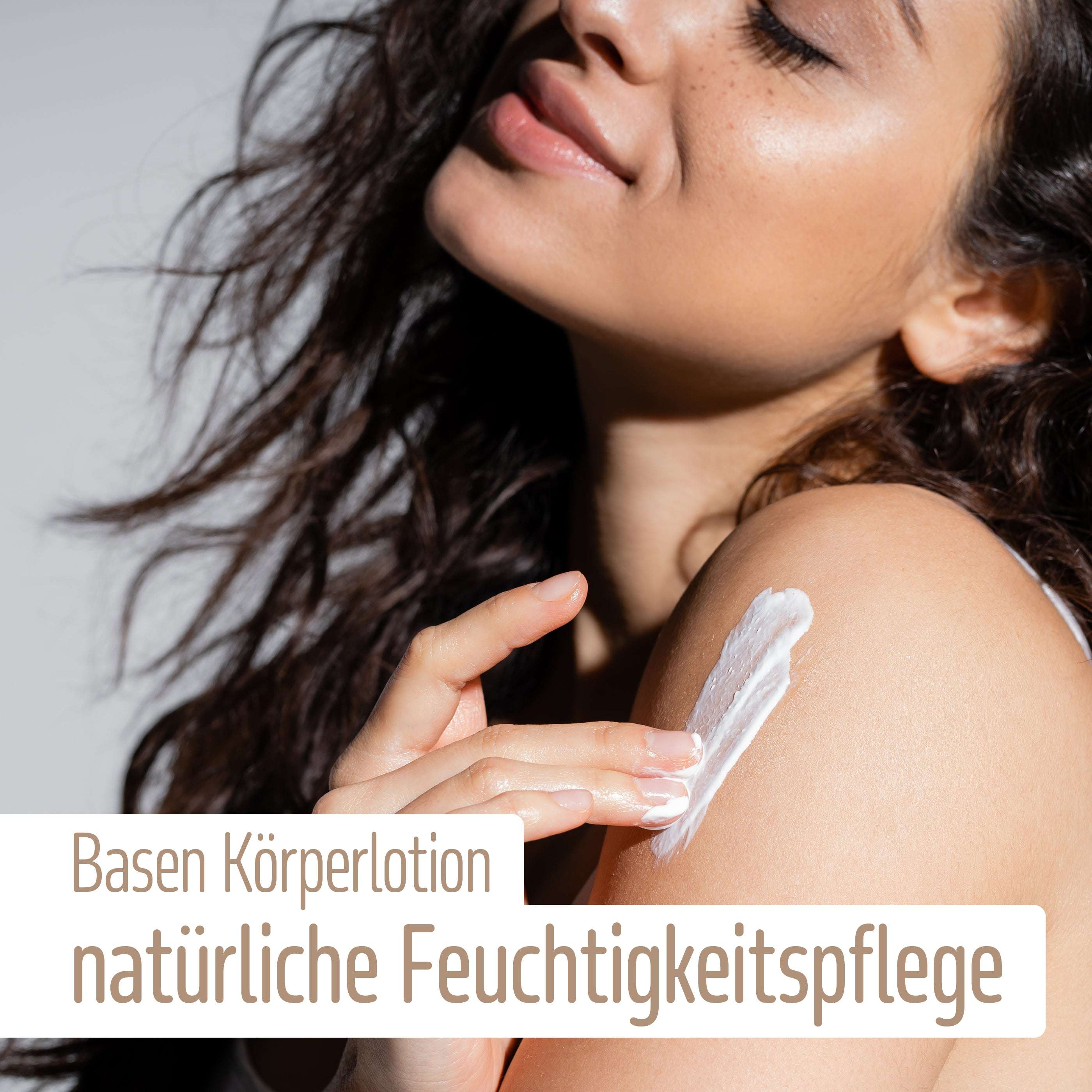 Eine Frau mit langen braunen Haaren trägt weiße Lotion auf ihre Schulter auf. Der Text auf dem Bild lautet: fitne Basische Körperlotion, mit Bio-Mandelöl für natürlich mit Feuchtigkeit versorgte Haut.